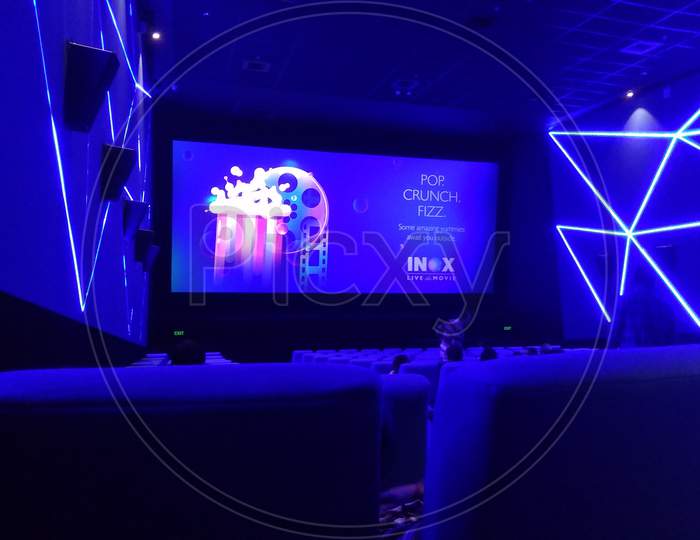 Kolkata, West Bengal/India - January 1, 2019: Blue seats or chairs and hall wall's and screen display under dim light inside INOX movie hall at Madhyamgram, Star Mall.