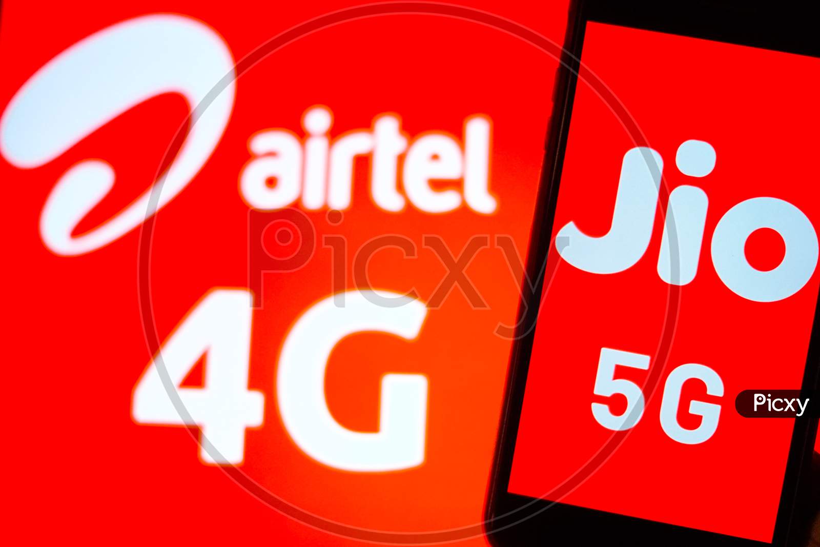 Close Up shot of a Mobilephone or Smartphone with Jio 5G on Screen and Airtel Logo in the Background - A Concept of Jio 5G vs Airtel 4G