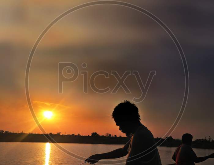 Fisher Mans At Sunset In The Lake While His Catching Fishes With Net