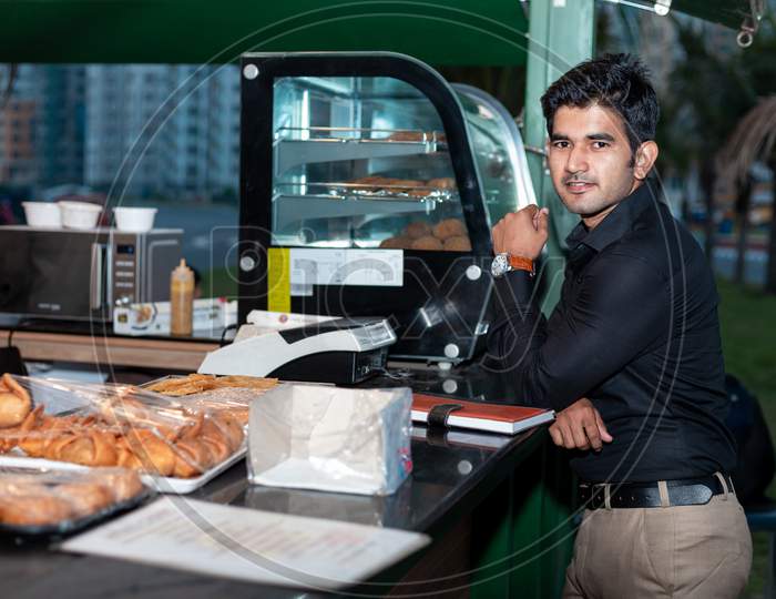 Young Entrepreneur standing near cafe shop with a dairy in his hand , Tea break and evening breakfast concept.