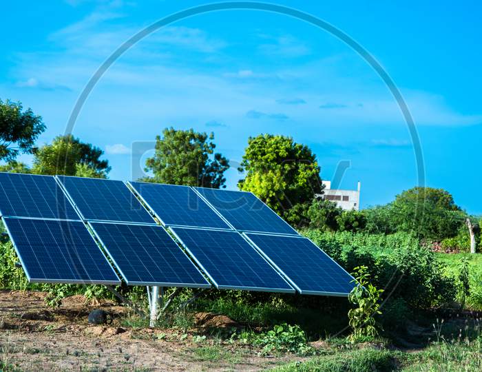 Small Solar Panel Setup Installed In Agriculture Field With Blue Sky, Green Environment.