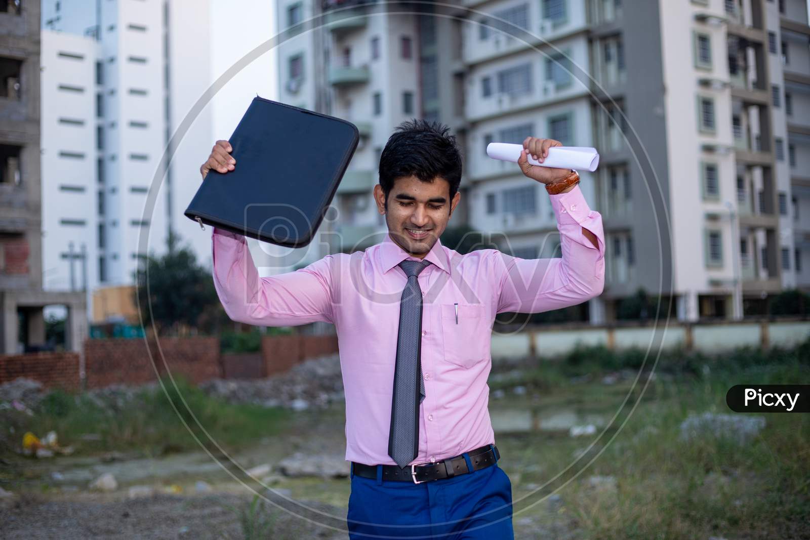 Happy ecstatic Indian businessman or Student with files and both hands raised in the air . Man celebrating Joy after successful Project.