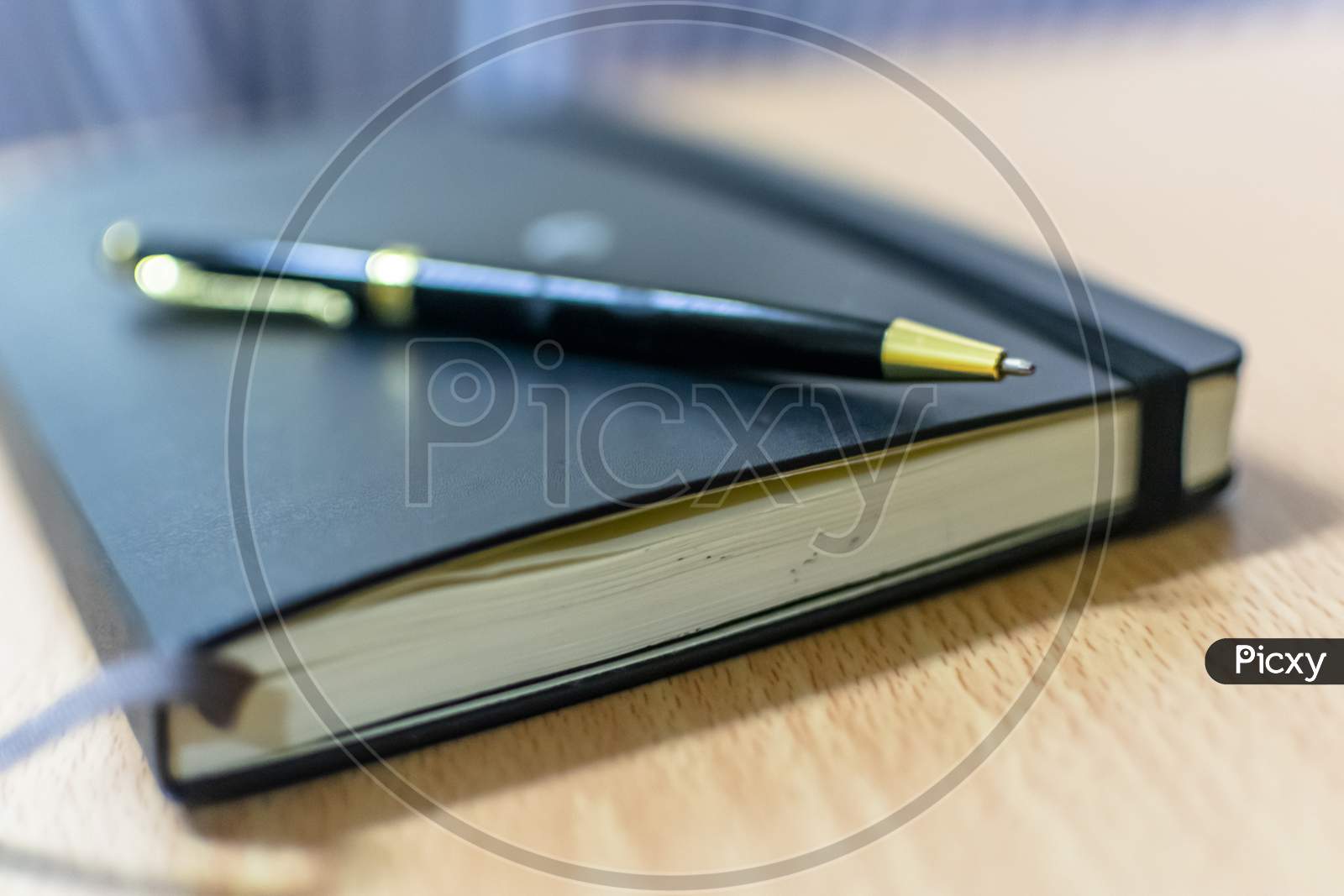 A Note Book And A Black Pen On An Office Table