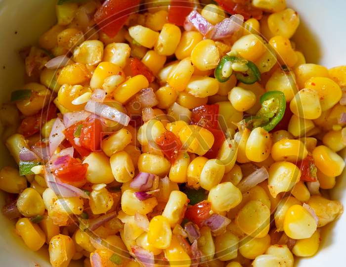 Spicy boiled corn salad. Chatpata sweet corn snacks prepared with tomatoes, onions and spices.