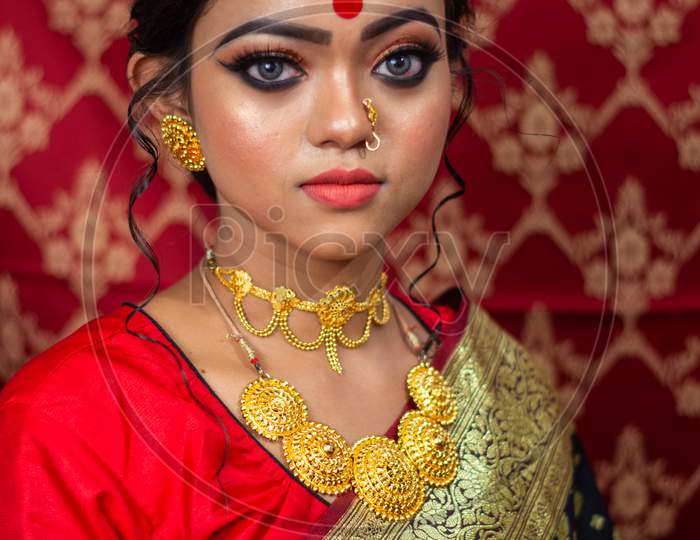 Portrait Of A Beautiful Elegant Female Model In Traditional Ethnic Indian Asian Bridal Costume With Makeup And Heavy Jewellery, Looking At Camera