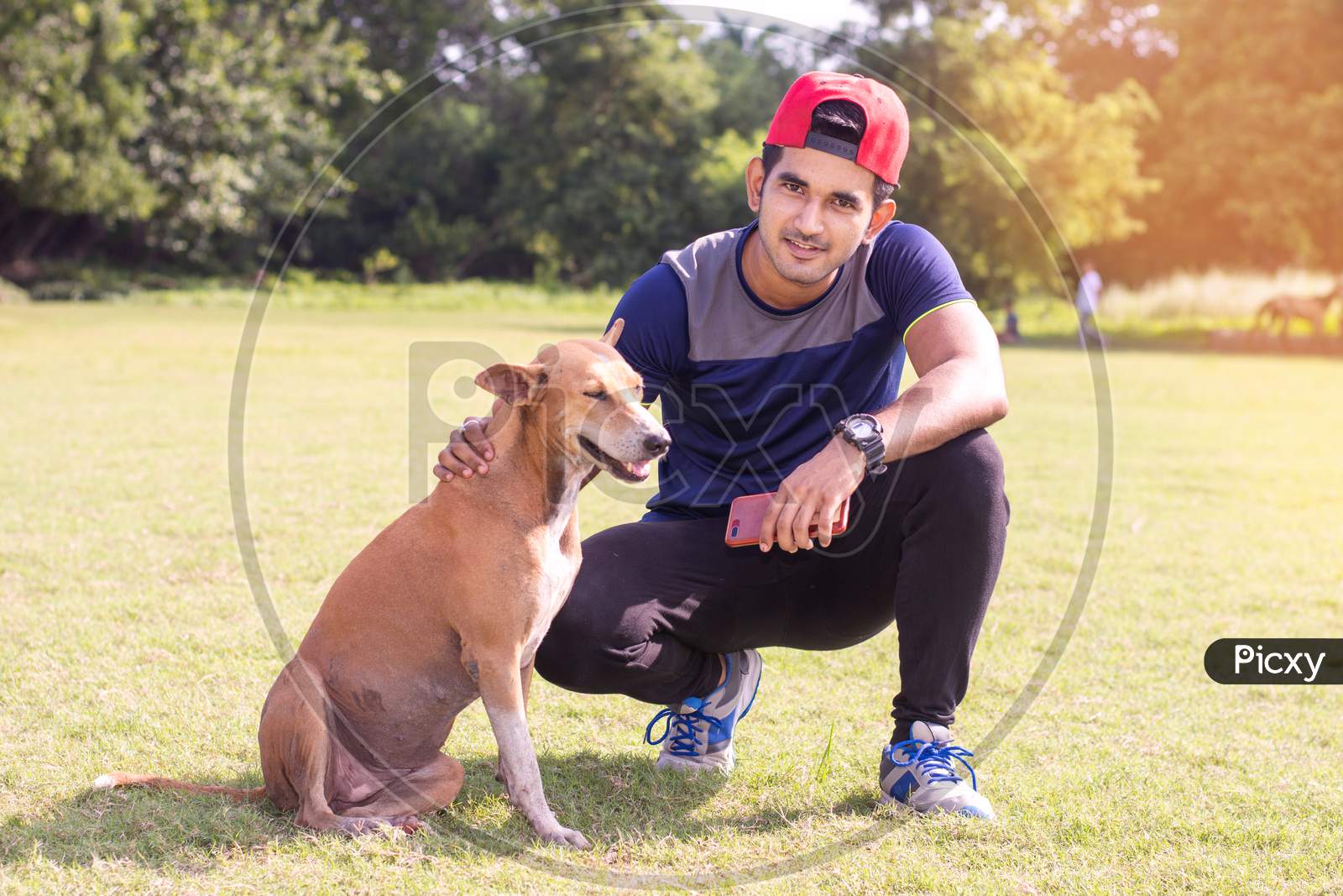 Image of Young Indian sports man playing with dog in sports ground while  jogging. Male Sports and fitness concept.-ZN579295-Picxy