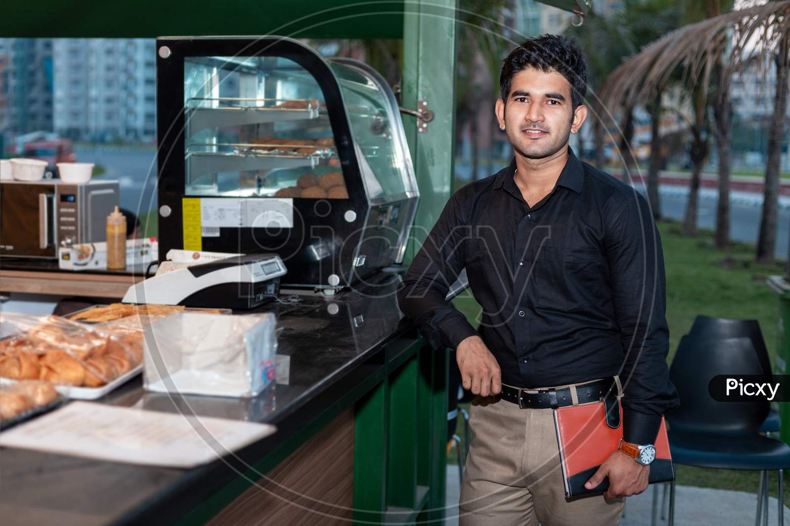 Young Entrepreneur standing near cafe shop with a dairy in his hand , Tea break and evening breakfast concept.
