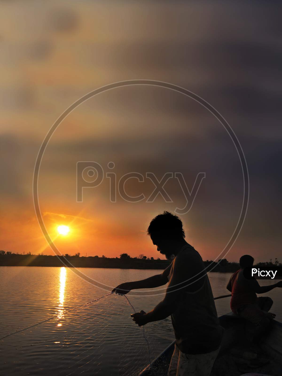 Fisher Mans At Sunset In The Lake While His Catching Fishes With Net