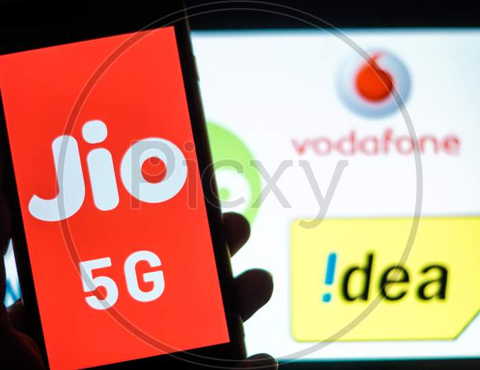 Close Up shot of a Mobilephone or Smartphone with Jio 5G on Screen and idea and Vodafone Logo in the Background - A Concept of Jio 5G vs Idea 4G and Vodafone 4G