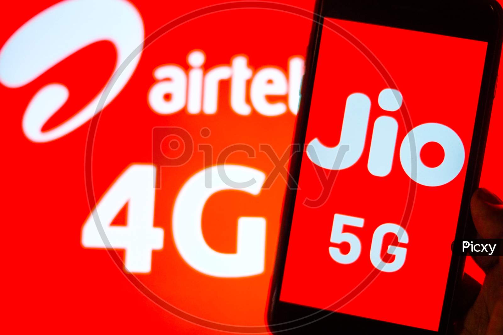 Close Up shot of a Mobilephone or Smartphone with Jio 5G on Screen and Airtel Logo in the Background - A Concept of Jio 5G vs Airtel 4G