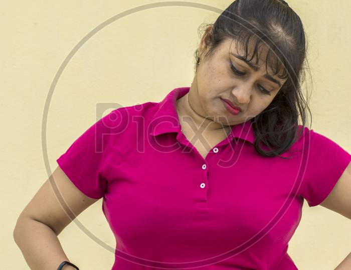 Indian Female Model Looking Down Unhappy With Her Fat Belly In Yellow Background With Copy Space For Text