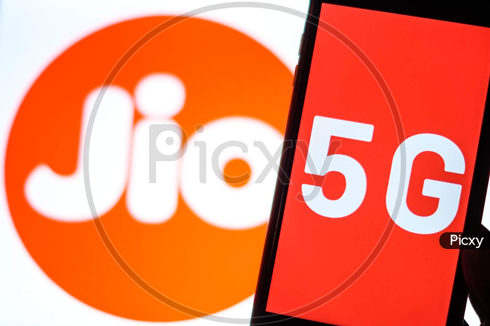 Close Up shot of a Mobilephone or Smartphone with 5G on Screen and Jio Logo in the Background - A Concept of Jio 5G