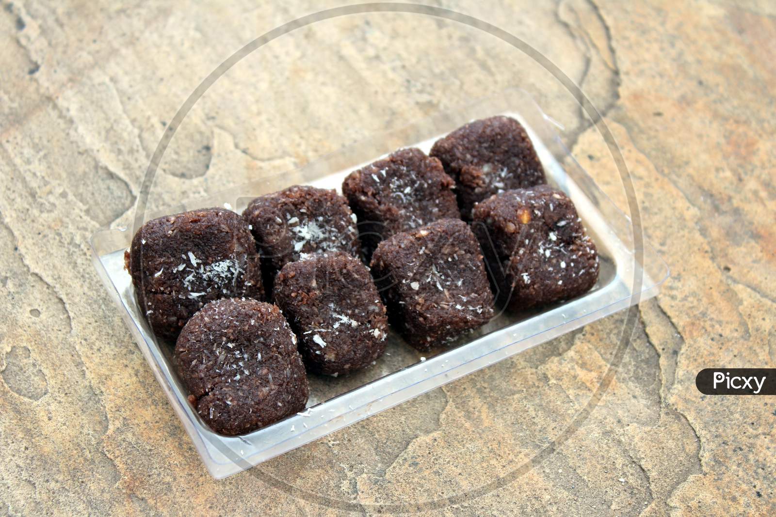 some chocolate sweets put in a glass tray on stone background