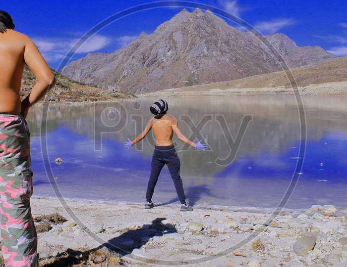 tourists or hikers are expressing their feelings and excitement infront of frozen sela lake, beautiful alpine lake is located in high himalayan region near sela pass, on the border between tawang and west kameng district in arunachal pradesh, north east india