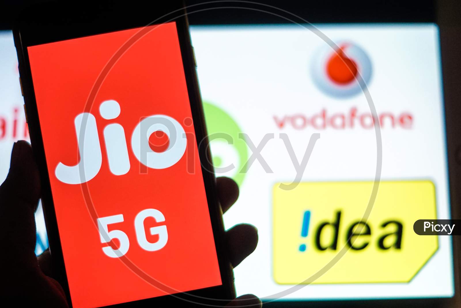Close Up shot of a Mobilephone or Smartphone with Jio 5G on Screen and idea and Vodafone Logo in the Background - A Concept of Jio 5G vs Idea 4G and Vodafone 4G