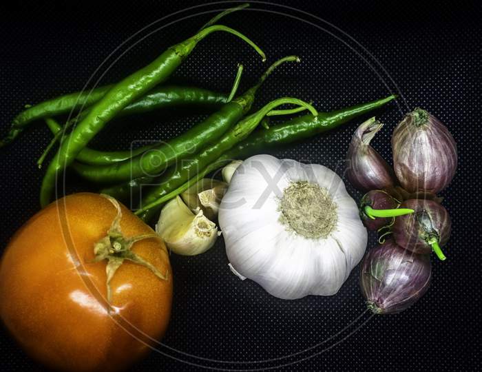 Mix Vegetables In Black Background, Garlic, Tomato And Green Chilli