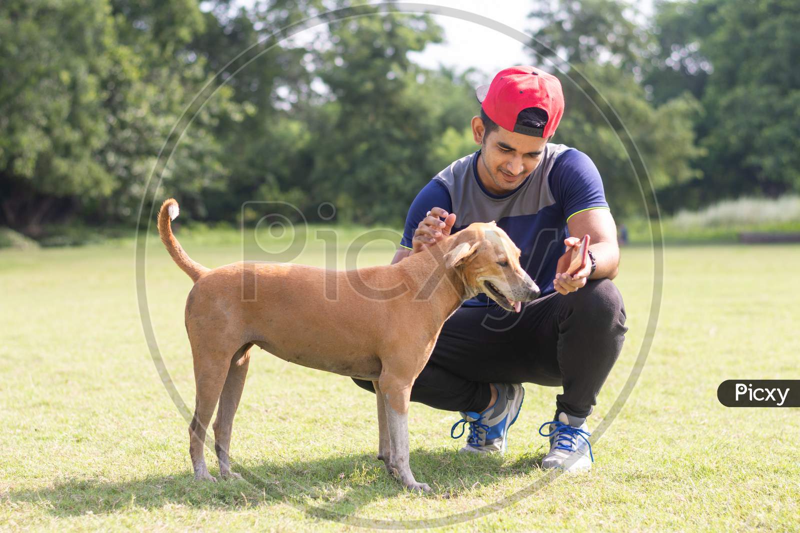 Young Indian sports man playing with dog in sports ground while jogging. Male  Sports and fitness concept.