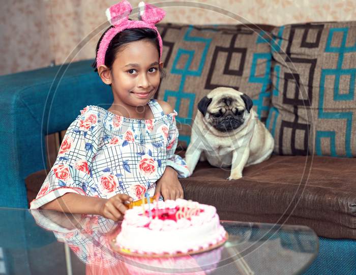 A happy girl and dog celebrating birthday. Party, cake, friendship with pet animal concept.
