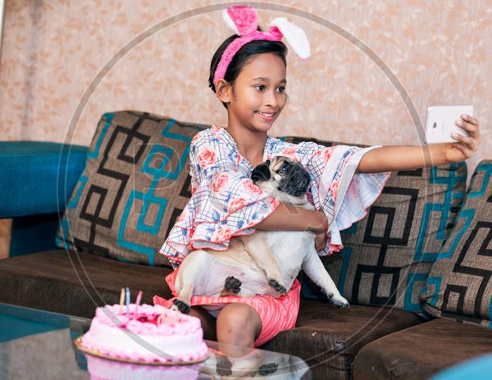 A happy girl and dog celebrating birthday. Party, cake, friendship with pet animal concept.