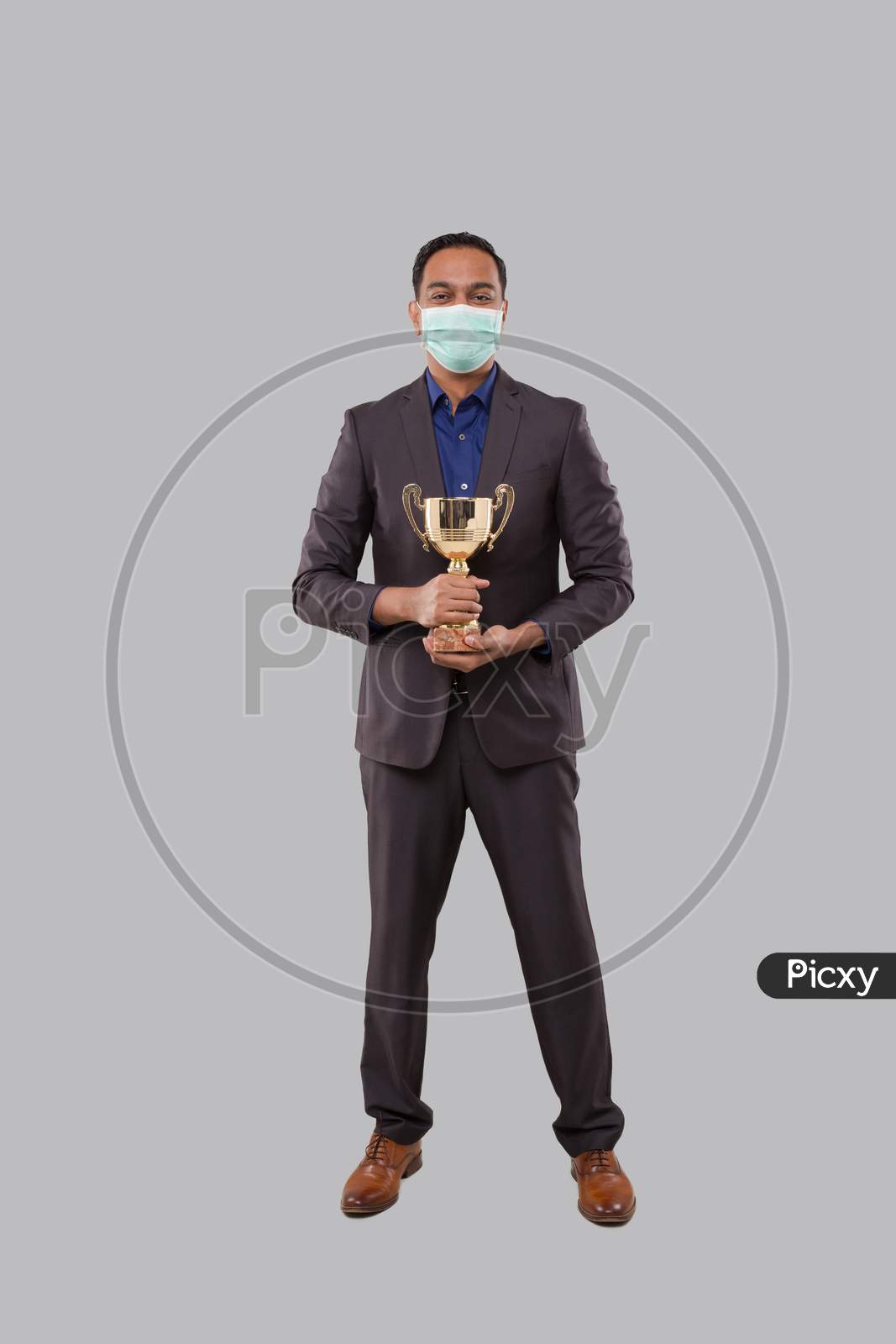 Businessman Holding Trophy Wearing Medical Mask. Indian Businessman Standing Full Length With Trophy In Hands