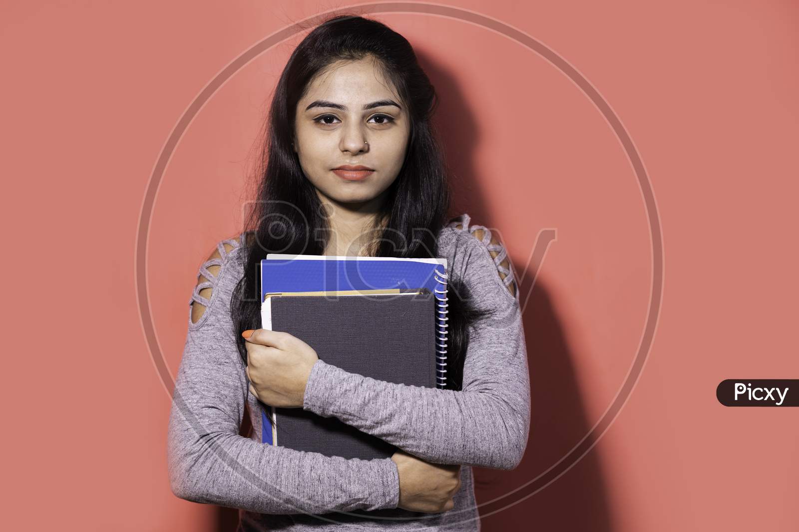 Smiling Indian female student holding books and file , college or school student and education concept.