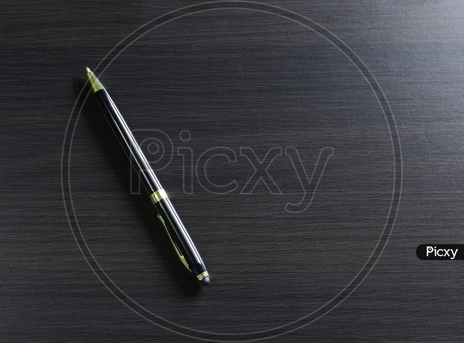 A Pen Laying On A Black Table With Window Light