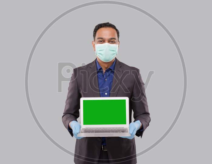 Businessman Showing Laptop Green Screen Wearing Medical Mask And Gloves Isolated. Indian Business Man With Laptop In Hands. Online Business Concept