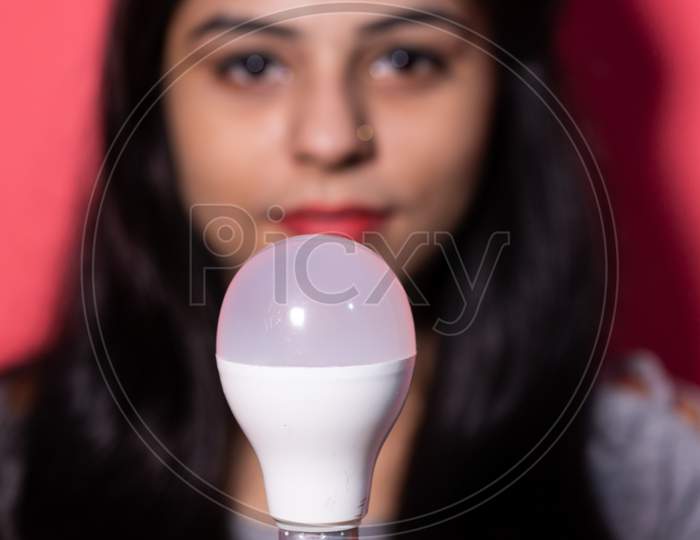 Pretty young woman holding a luminous led light bulb. Green energy , saving of energy with led bulb.