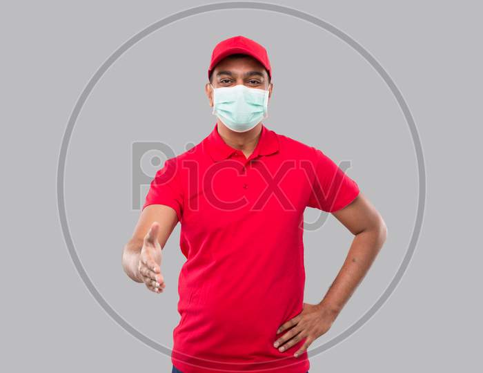 Indian Delivery Man Offering Hand To Shake Wearing Medical Mask Isolated. Greeting And Welcoming Gesture. Delivery Advertisement Concept. Delivery Man Hand Shake. Delivery Boy
