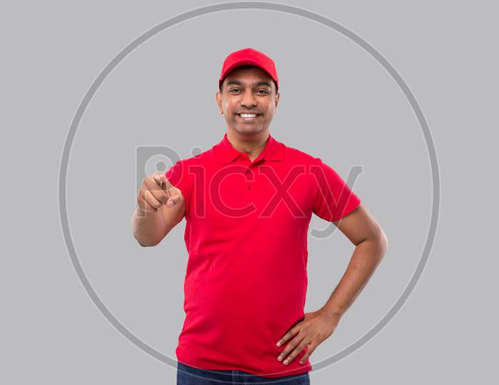 Delivery Man Pointing In Camera. Indian Delivery Boy In Red Uniform Isolated