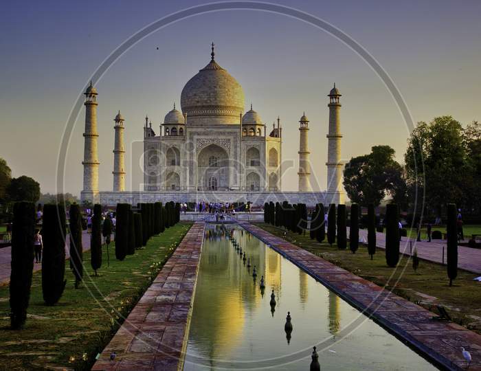 Agra, India - April 10,2014: Wide Angle Of Tajmahal With It'S Reflection In The Fountain Pond, One Of The Seven Wonder Partially Lit Under Dramatic Sunrise