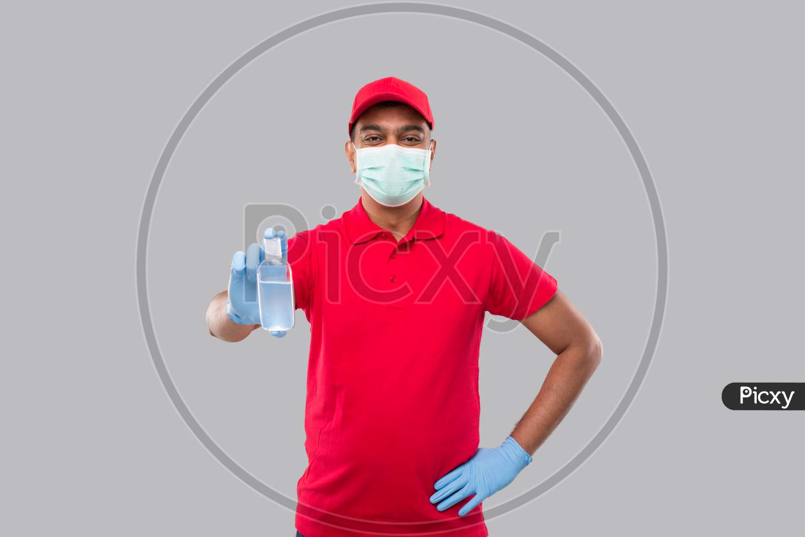 Delivery Man Showing Hands Sanitizer Wearing Medical Mask And Gloves Isolated. Indian Delivery Boy Holding Hand Antiseptic