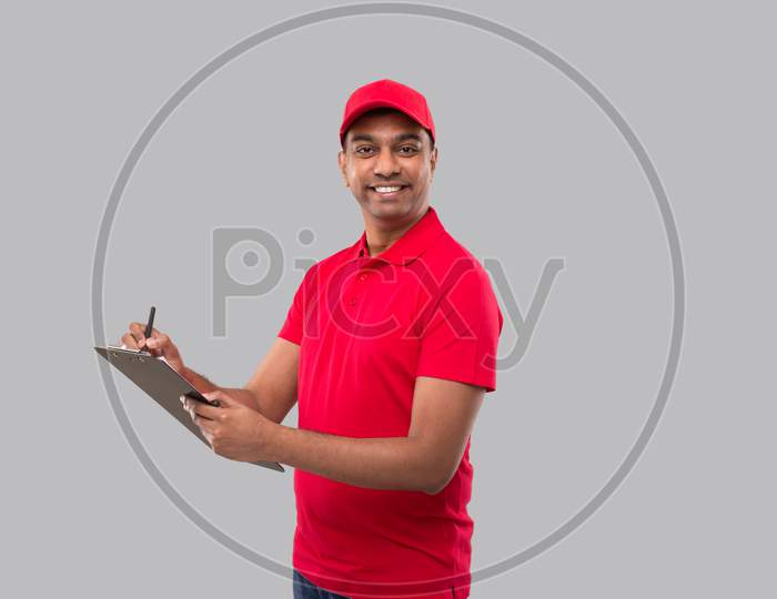 Delivery Man Writing In Clipboard Watching In Camera. Indian Delivery Boy Clipboard