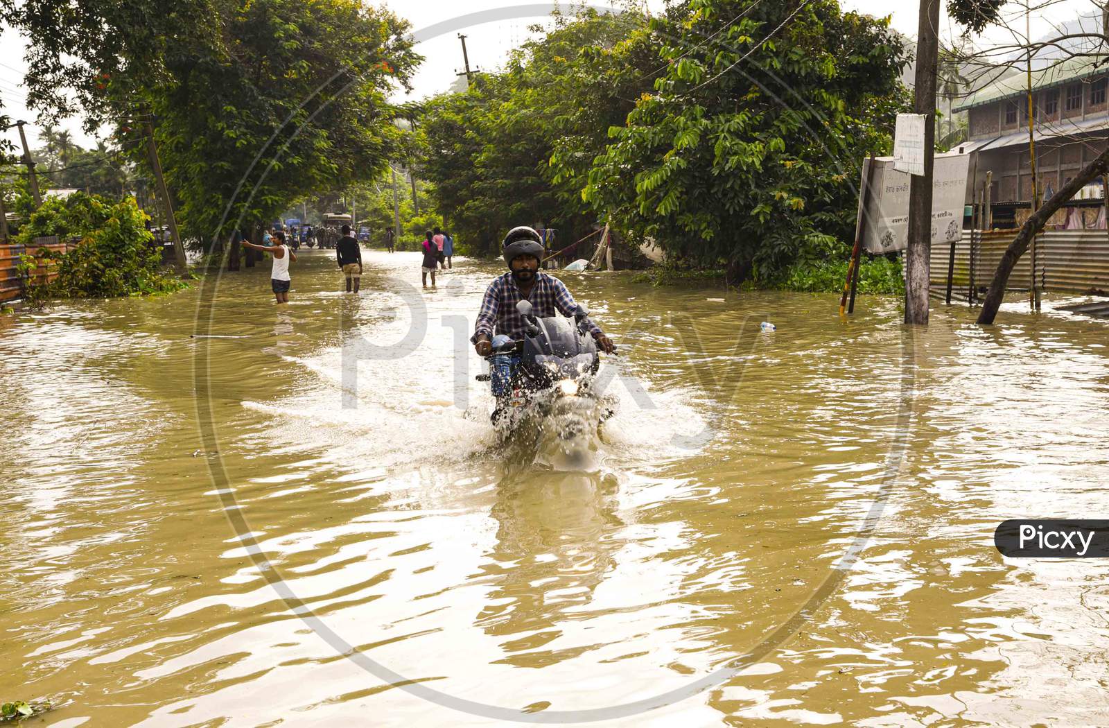 Bikers  move through a flood  water road