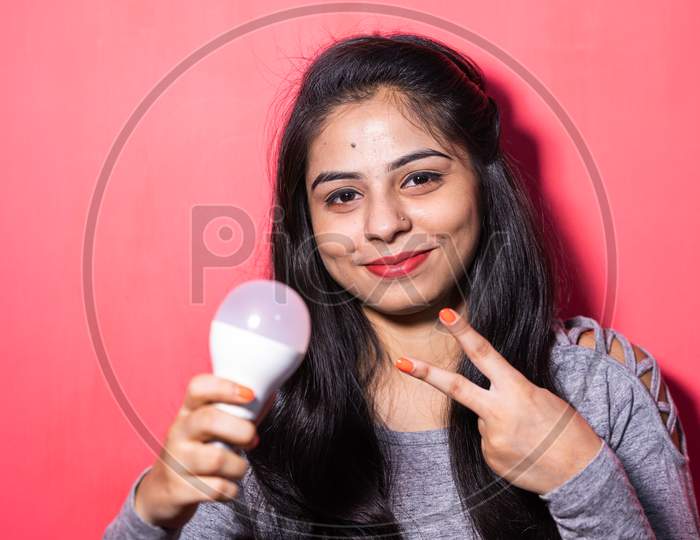 Pretty young woman holding a luminous led light bulb. Green energy , saving of energy with led bulb.