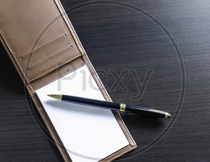 A Pen And Small Daily Note On A Black Table
