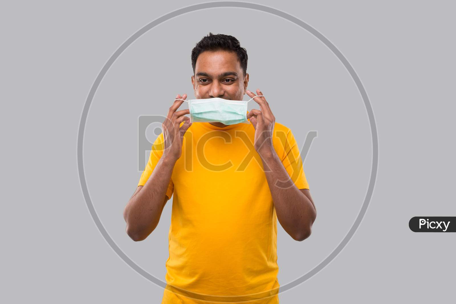 Indian Man Puts On Medical Mask In Yellow Tshirt Isolated