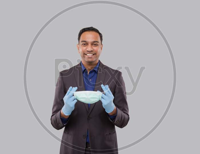 Businessman Puts On Medical Mask Wearing Gloves Isolated. Indian Business Man With Medical Mask In Hands