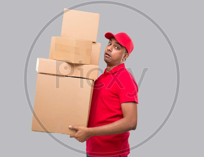 Delivery Man Holding A Lot Carton Boxes Isolated. Indian Delivery Boy Overloaded With Boxes. Heavy Boxes