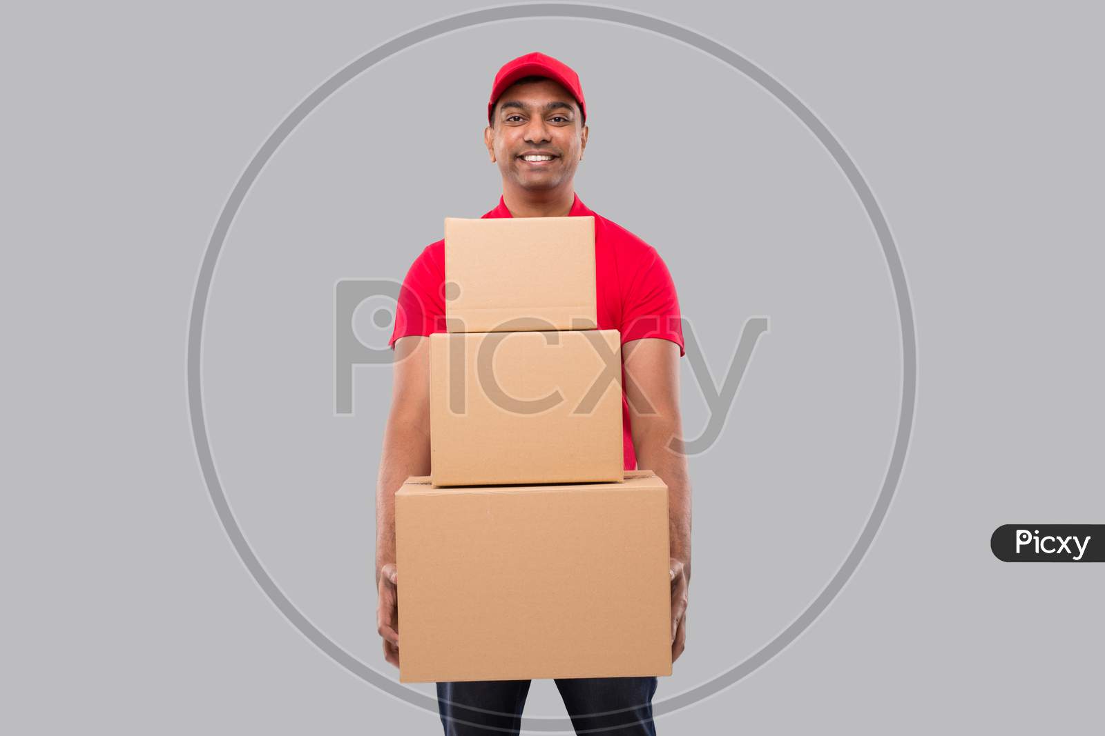 Delivery Man Holding Carton Boxes Isolated. Indian Delivery Boy Smiling With Boxes In Hands