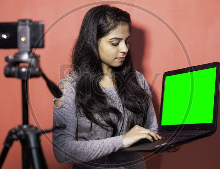 A young woman taking virtual online classes on smartphone and laptop. Concept of e-teaching, virtual online video classes, self isolated quarantine lifestyle and education in India.