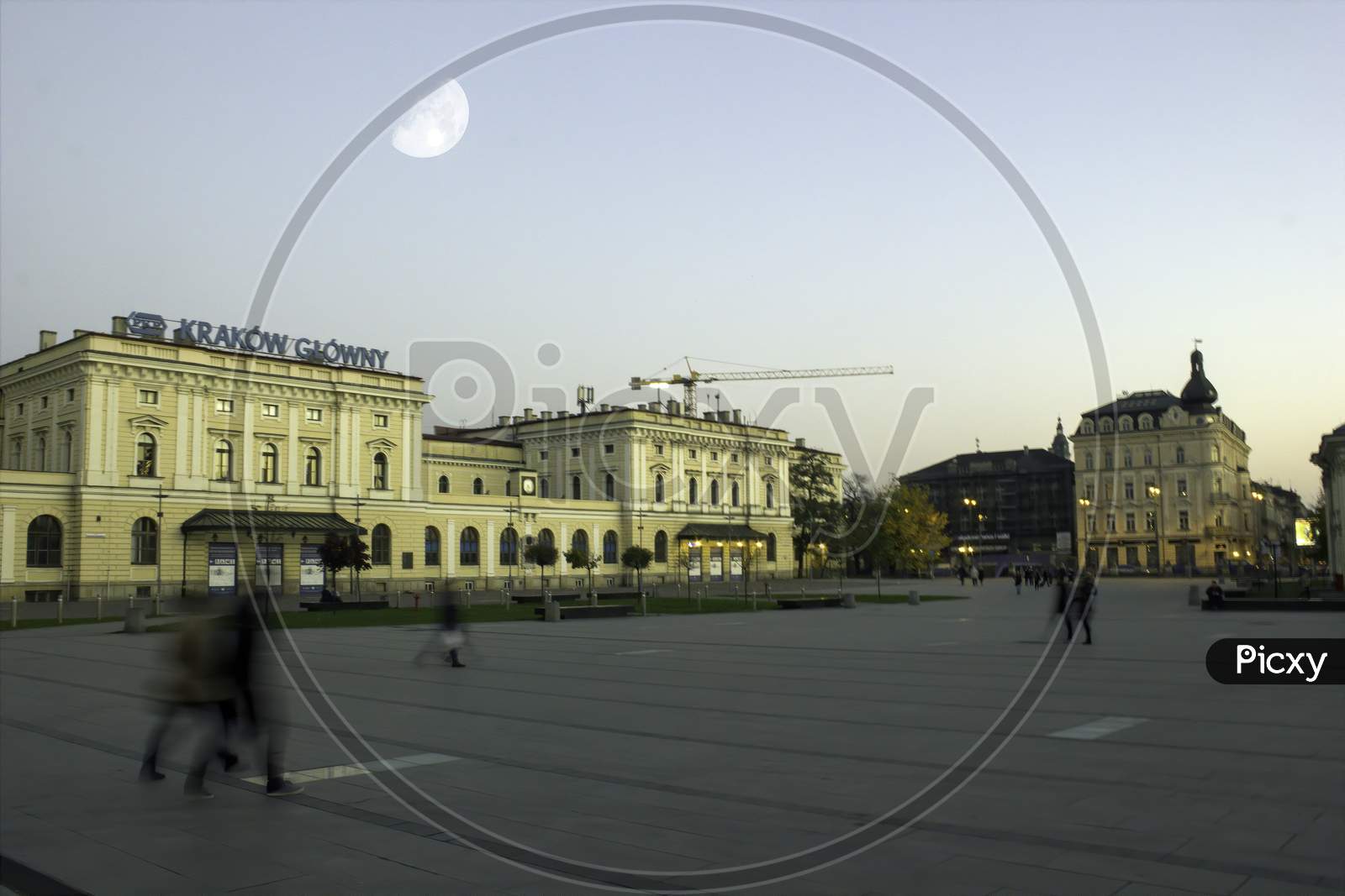 Krakow, Poland - November 02, 2014: Wide Angle View Of Main Square Under Moon And Tourists Walking In Motion Blur