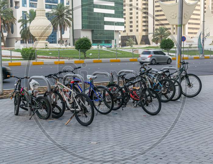A Group Of Bycicles Parked In A Parking Space In Abu Dhabi Street.A Group Of Bicycles Parked In A Parking Space In Abu Dhabi Street.