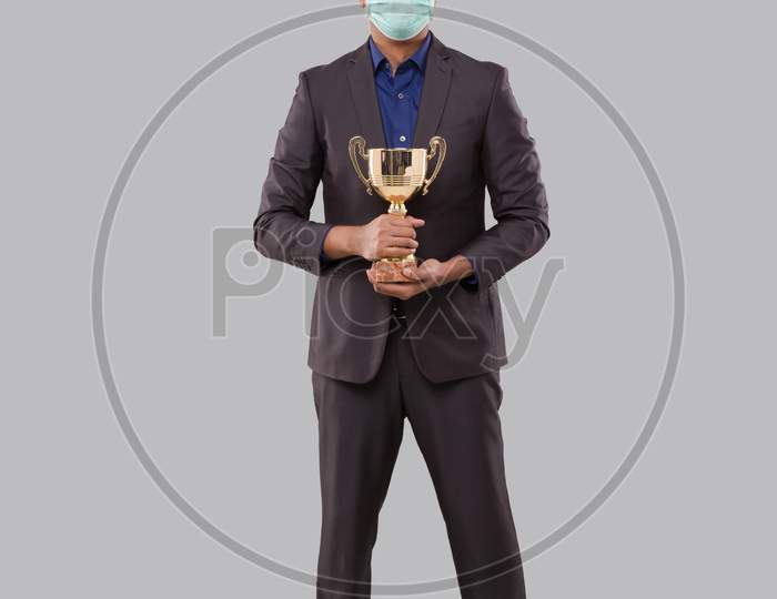 Businessman Holding Trophy Wearing Medical Mask. Indian Businessman Standing Full Length With Trophy In Hands
