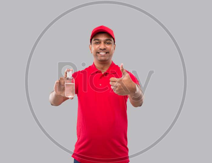 Indian Delivery Man Holding Hands Sanitizer Showing Thumb Up. Hands Antiseptic. Man In Red T Shirt. Health, Isolation Concept