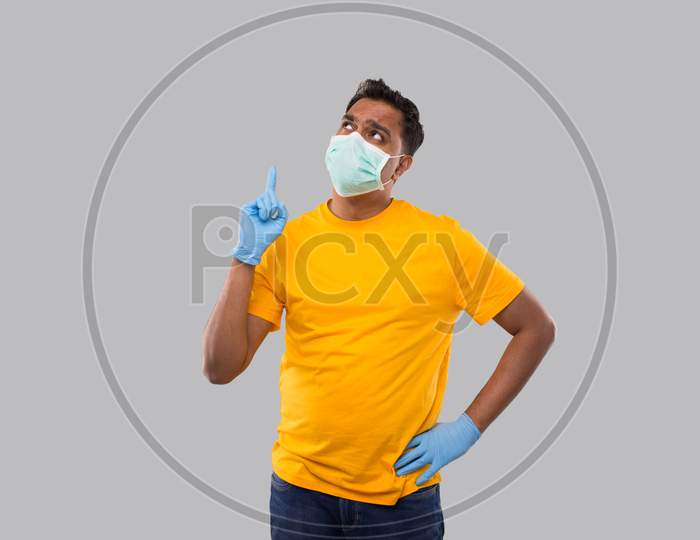 Indian Man Pointing Up Wearing Medical Mask And Gloves Isolated. Man Thinking
