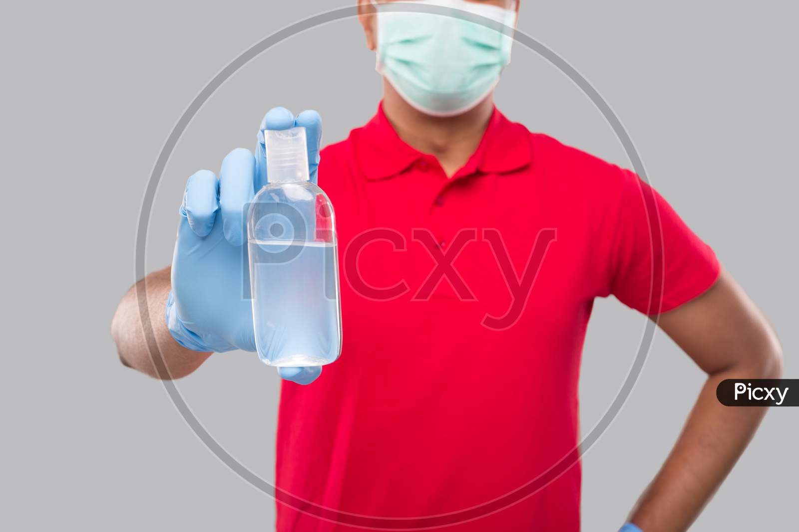 Delivery Man Showing Hands Sanitizer Wearing Medical Mask And Gloves Isolated. Indian Delivery Boy Holding Hand Antiseptic Close Up