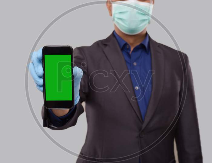 Businessman Showing Phone Wearing Medical Mask And Gloves Close Up. Indian Business Man Technology Business At Home. Phone Green Screen Isolated