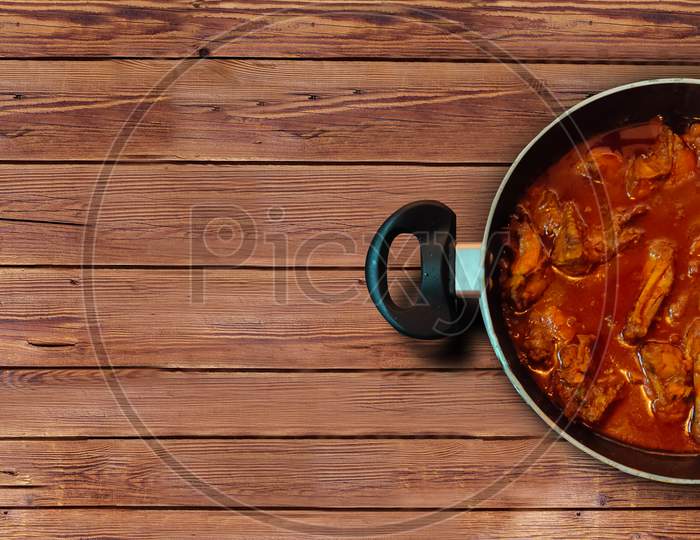 Chicken curry in kadai on wooden table