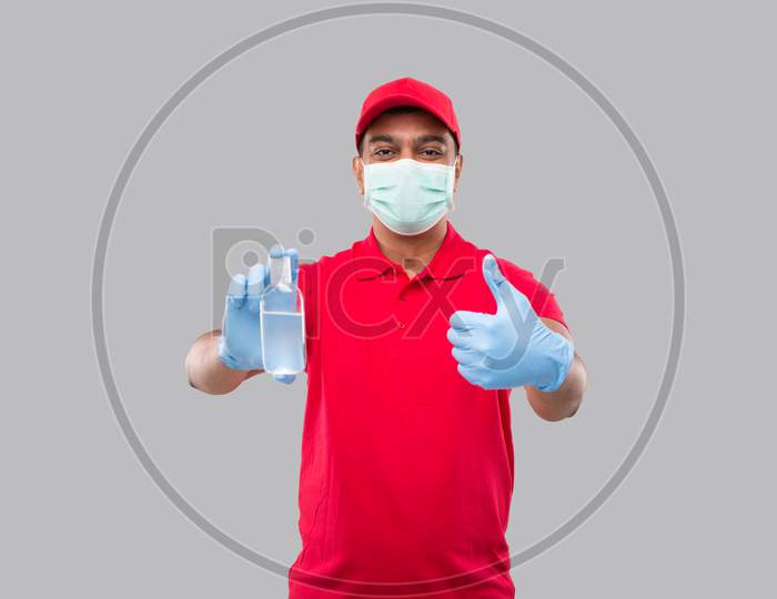Delivery Man Showing Hands Sanitizer And Thumb Up Wearing Medical Mask And Gloves Isolated. Indian Delivery Boy Holding Hand Antiseptic